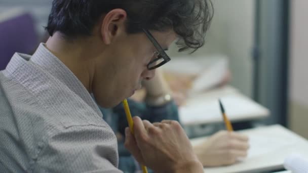 画面的西班牙裔学生写作与演讲时眼镜在拼贴的教室里. — 图库视频影像