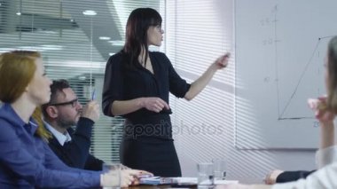 İş kadını bir toplantı odasında oturuyorsun çalışanların bir takım için bir sunum yapıyor.