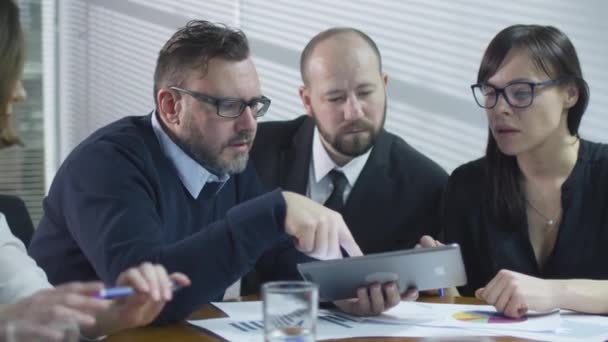 Grupp av anställda har en konversation i mötesrummet. Affärsman använder en tablet PC. — Stockvideo