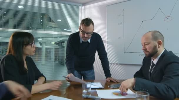 Empresário está fazendo uma apresentação para uma equipe de funcionários que estão sentados em uma sala de reuniões . — Vídeo de Stock