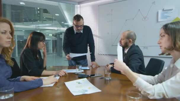 Empleado está haciendo una presentación para un equipo de colegas que están sentados en una sala de reuniones . — Vídeos de Stock