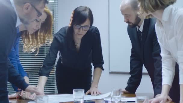 Kvinnlig anställd är att göra en presentation för ett team av kollegor som sitter i ett mötesrum. — Stockvideo