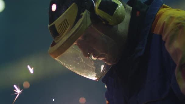 Retrato de un trabajador de la industria pesada en una máscara que refleja chispas mientras trabaja con metal en una amoladora angular . — Vídeos de Stock