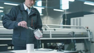 Kask içinde kıdemli mühendis metal nesneleri ölçme ve verileri bir tablet bilgisayar ile bir fabrikada kaydeder.