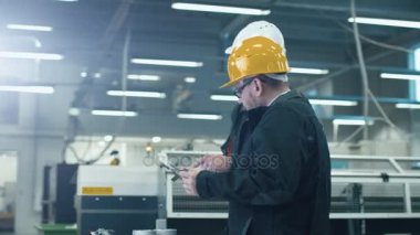 Bir fabrikada bir tablet bilgisayardaki bilgileri denetlenirken bir plan iki mühendis tartışmak.