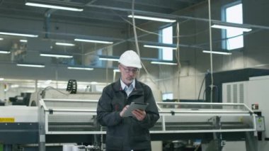 Kask içinde kıdemli mühendis bir fabrikada bir tablet bilgisayar kullanıyor.