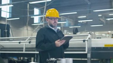 Kask içinde kıdemli mühendis bir fabrikada bir tablet bilgisayar kullanıyor.