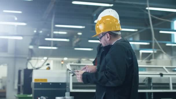 Dois engenheiros discutem um plano enquanto verificam informações em um computador tablet em uma fábrica . — Vídeo de Stock