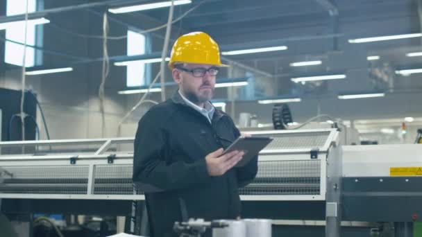 Ingeniero senior en hardhat está utilizando una tableta en una fábrica . — Vídeo de stock