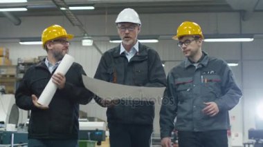 Kıdemli mühendis ve iki işçi ile kağıtları fabrika uzayda yürüyor.