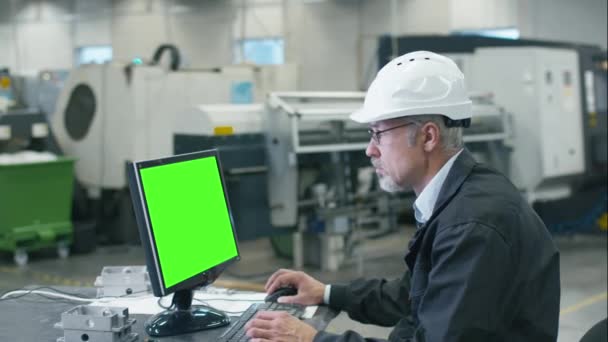 Ingeniero sénior en gafas está trabajando en una computadora de escritorio en una fábrica . — Vídeos de Stock