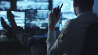 Güvenlik görevlisi bilgisayar masa başında rahatlatıcı ise karanlık bir izleme odada kahve içme göstermek perde ile dolu.