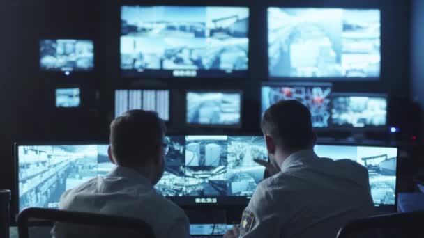 Dva bezpečnostní důstojníci si všiml vetřelcem na obrazovce počítače sledování v tmavé místnosti, sledování.