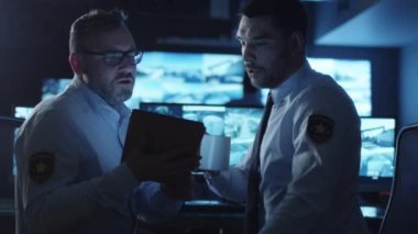 Güvenlik görevlisi karanlık bir izleme odada göstermek perde ile dolu bir tablet bilgisayar kullanıyor.