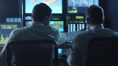 İki çalışanı göstermek perde ile dolu bir hava tahmini merkezinde bulunan bilgisayarlarda çalışma.