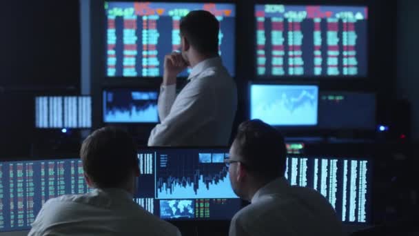 Team of successful stockbrokers celebrate reached goals in dark office with display screens. — Stock Video
