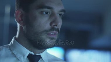 Yöneticisi bir bilgisayarda göstermek perde ile dolu bir karanlık office odada akşam çalışıyor.