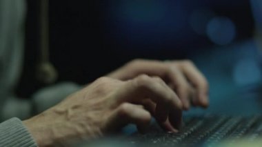 Yazma ve bir karanlık office odada bir bilgisayarda çalışan erkek çalışan konsantre.