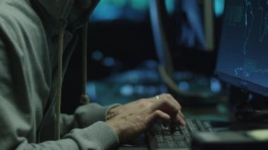 Haritalar ve veriler üzerinde göstermek perde bir karanlık office odada bulunan bir bilgisayarda bir Hood erkek hacker çalışır.