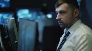 Programcılar ile dolu bir karanlık office odada bulunan bilgisayarlar üzerinde çalıştığınız iki BT görüntüleme ekranları.