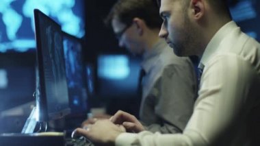 Programcılar ile dolu bir oda karanlık ofis içinde bilgisayar üzerinde çalıştığınız iki BT görüntüleme ekranları.