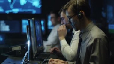 Programcılar kulaklık ile dolu bir karanlık office odasında bilgisayar üzerinde çalıştığınız iki BT görüntüleme ekranları.
