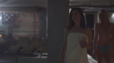 Genç çekici kadın bir spa Sağlık Merkezi bir havlu havuz boyunca yürüyüş.