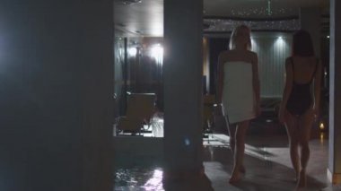 Genç çekici kadın bir spa Sağlık Merkezi bir havlu havuz boyunca yürüyüş.