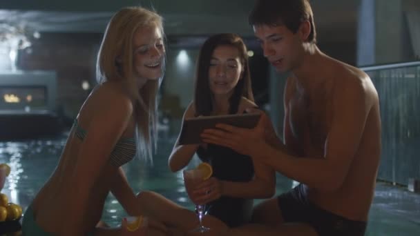 Gruppo di amici si stanno divertendo mentre utilizzano un tablet vicino a una piscina in un centro benessere spa . — Video Stock