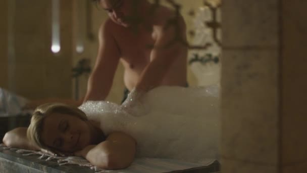 Joven hermosa hembra es relajante durante un masaje de jabón turco en un centro de bienestar spa . — Vídeo de stock