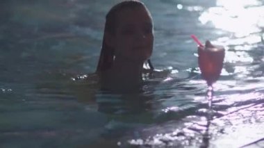Genç çekici kadın havuzdan alır ve bir spa Sağlık Merkezi bir kokteyl içer.