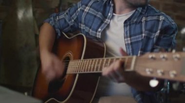 Ev stüdyosunda bir garaj bir şarkıda prova yaparken adam gitar çalıyor.