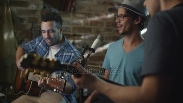 Banda cantar y tocar guitarras mientras graba una canción y practicar en un estudio en casa en un garaje . — Vídeo de stock