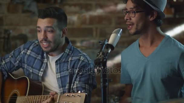 Banda cantar y tocar guitarras mientras graba una canción y ensayar en un estudio en casa en un garaje . — Vídeo de stock