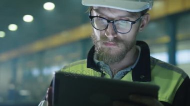 Kask mühendisi bir ağır sanayi fabrikada bir tablet bilgisayar kullanıyor.