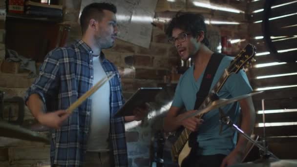 Μπάντα των μουσικών έχουν μια συζήτηση σε ένα στούντιο γκαράζ ενώ χρησιμοποιώντας έναν υπολογιστή tablet. — Αρχείο Βίντεο