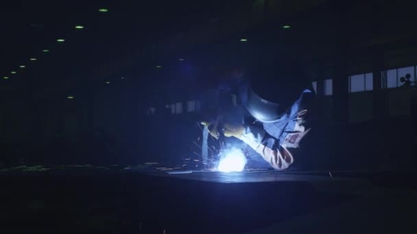 Travailleur de l'industrie lourde dans une usine soude le métal à l'intérieur sombre . — Video