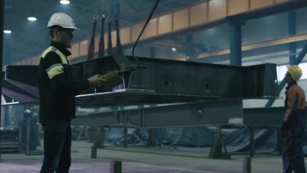 Arbeiter der Schwerindustrie bewegen ein massives Metallbauteil in einer Fabrik. — Stockvideo