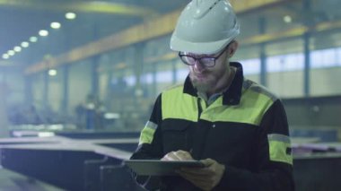 Kask mühendisi bir ağır sanayi fabrikada bir tablet bilgisayar kullanıyor.