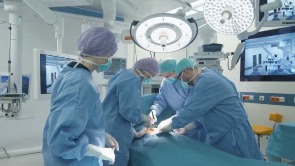 Медична команда проводить хірургічну операцію в яскравому сучасному операційному приміщенні — стокове відео