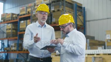 İki çalışanları iş tablet bilgisayar Lojistik merkezi depo ile görüşüyorlar.