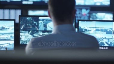 Güvenlik görevlisi karanlık bir izleme odada göstermek perde ile dolu bir bilgisayarda çalışıyor.