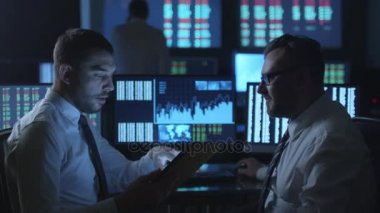 Borsacı bir tablet bilgisayar ile göstermek perde karanlık bir ofiste bir konuşma yaparken kullanıyor.