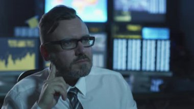 Yöneticisi bir bilgisayarda göstermek perde ile dolu bir karanlık office odada akşam çalışıyor.