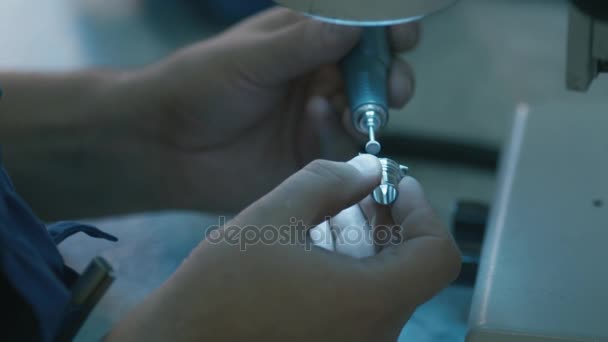 Ingeniero en una fábrica está puliendo un detalle de metal bajo un microscopio con linterna . — Vídeos de Stock