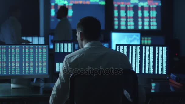 Stockbroker a repéré une tendance positive dans les graphiques de trading tout en travaillant dans une salle de surveillance sombre avec des écrans d'affichage . — Video