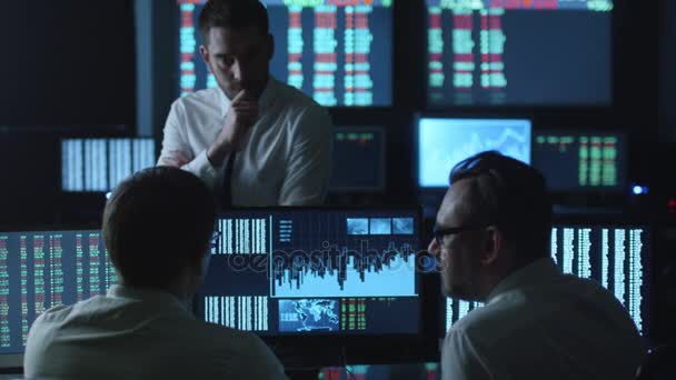 Team van de effectenmakelaars ondervindt een gesprek in een donkere kantoor met schermen. — Stockvideo