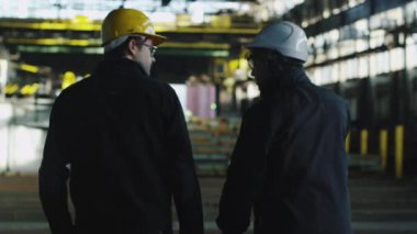 Endüstriyel alanda Vinçler ile yürüyen iki işçi zor şapka.