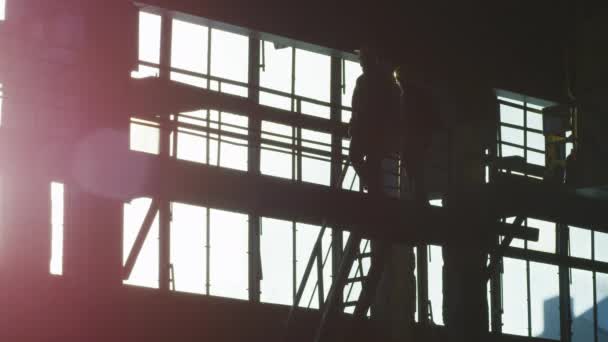 Silhouette de deux travailleurs sur chantier . — Video