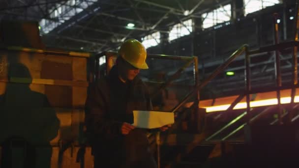 Technicien en chapeau dur marchant à travers la fonderie. Environnement industriel . — Video